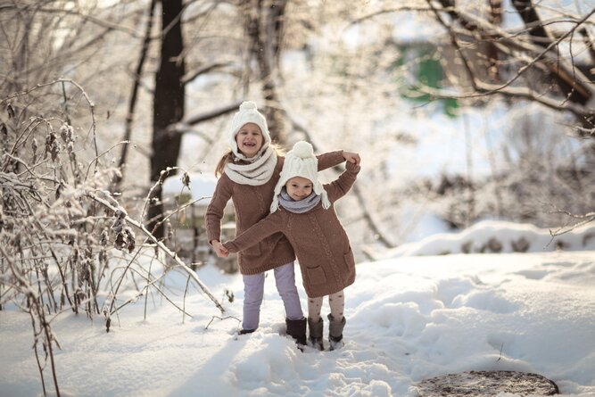 Two children in brown sweaters playing in the snow. | © www.natasha-lebedinskaya.com