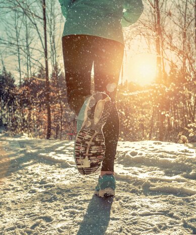 Close-up of running shoes on a snow-covered forest path | © Andrii Yurlov