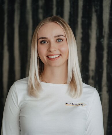 Lächelnde Frau trägt weißes Shirt mit Logo Schladming Apartments