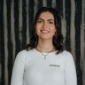 Lächelnde junge Frau in weißem Langarmshirt mit kleinem Logo