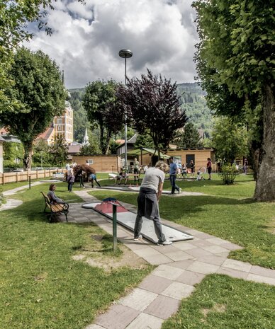 Town park with trees, benches, and people playing mini-golf | © Gerhard Pilz