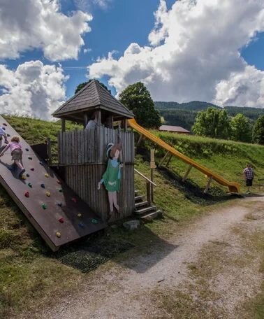 Children playing on a wooden playground with a slide