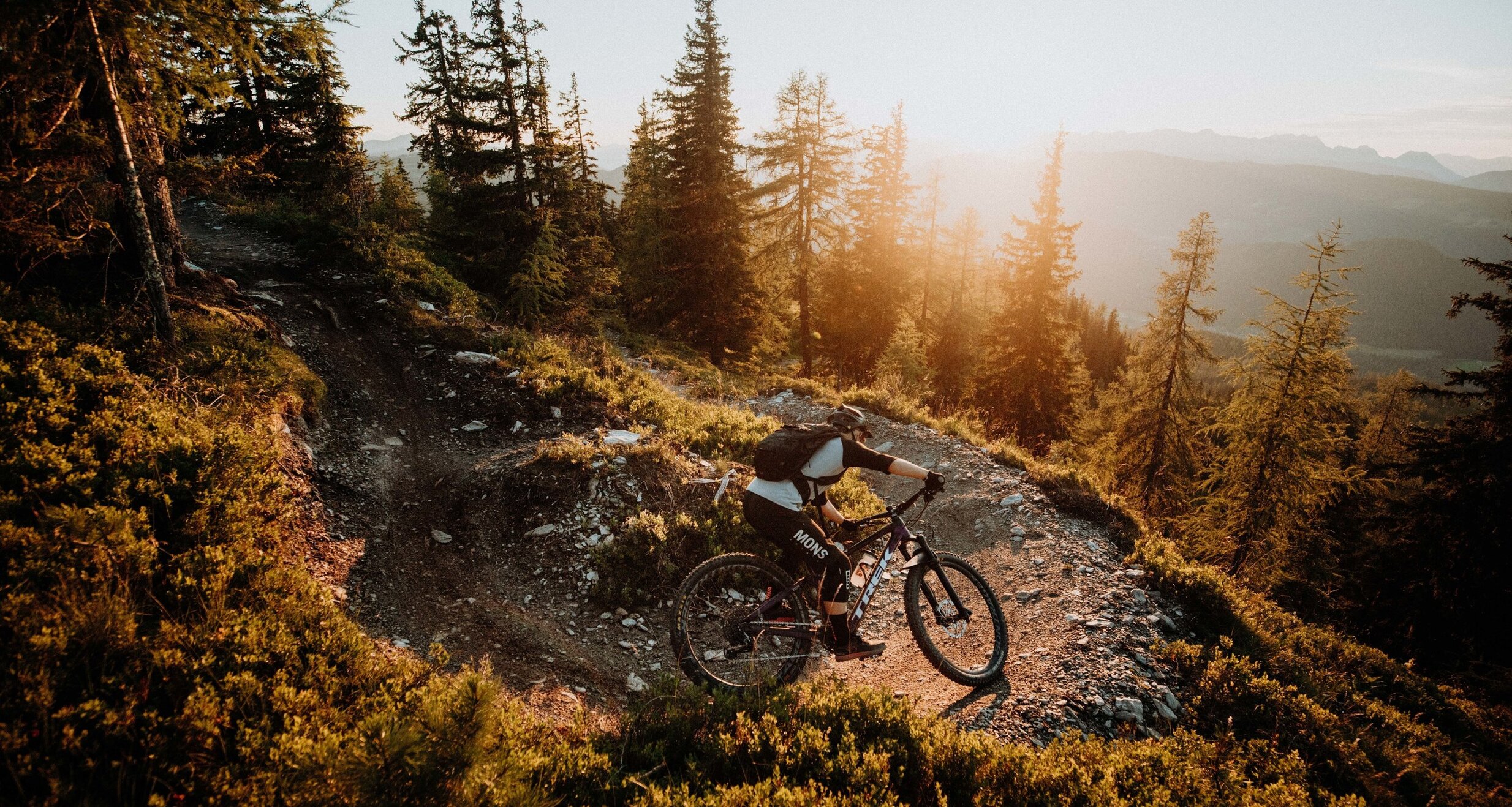 Mountain biker on a rocky forest trail at sunset
