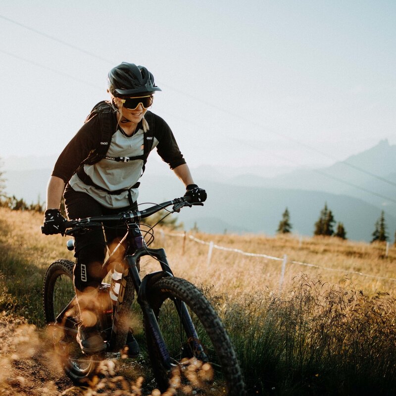 Mountain biker wearing helmet rides on a dirt trail with distant mountains