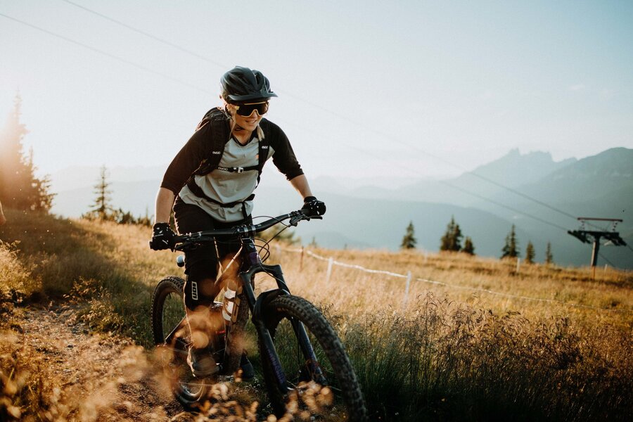 Mountain biker wearing helmet rides on a dirt trail with distant mountains