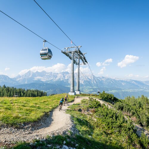 Cable car gondola over mountain landscape with cyclists | © Christoph Oberschneider