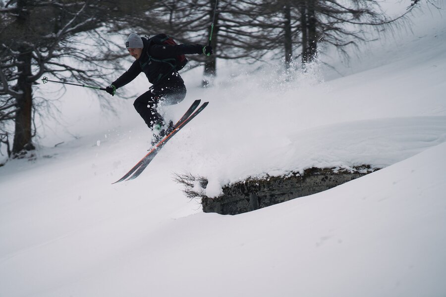 Skier in winter gear performing a jump off a snowy ledge | © Robert Maybach