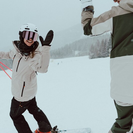 Snowboarder raises gloved hand for a high-five on snowy slope