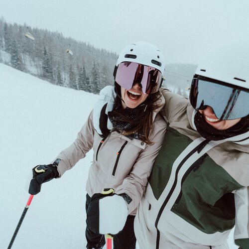 Two skiers in helmets and goggles on snowy slope