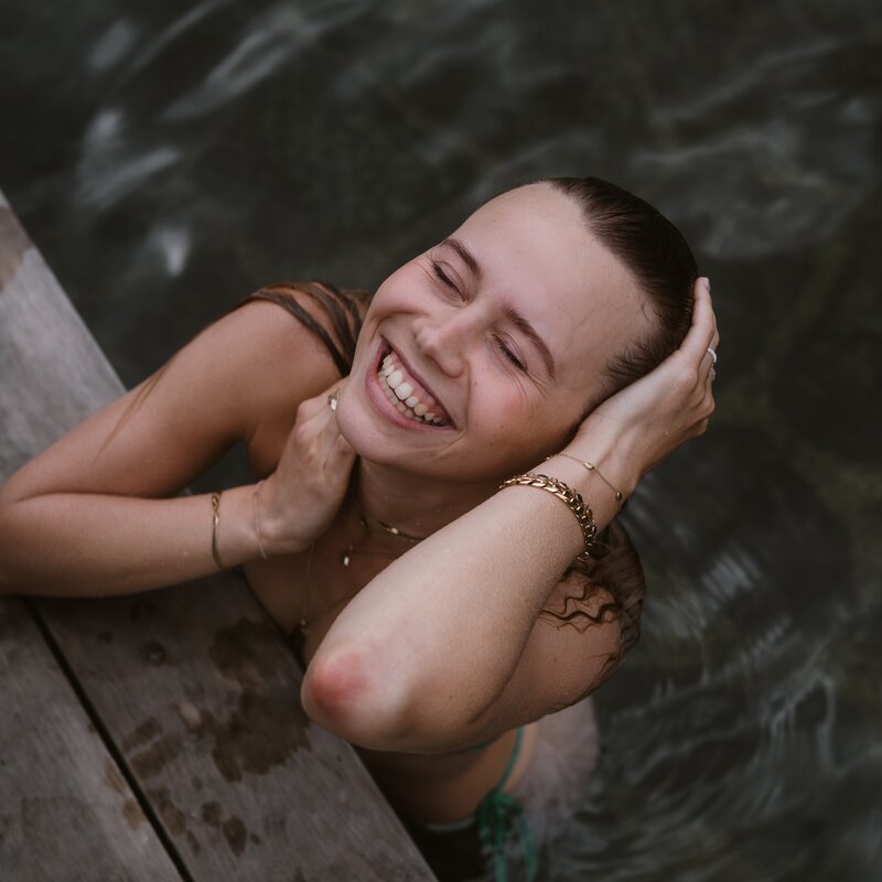 Smiling woman leaning on wooden dock above water