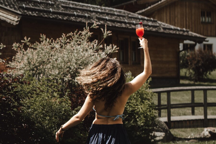 Back view of woman in blue skirt raising glass outdoors