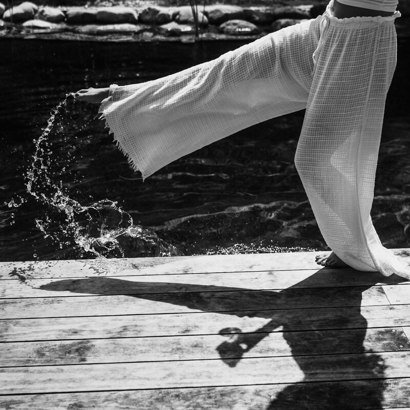 Person on wooden dock kicking water with extended leg