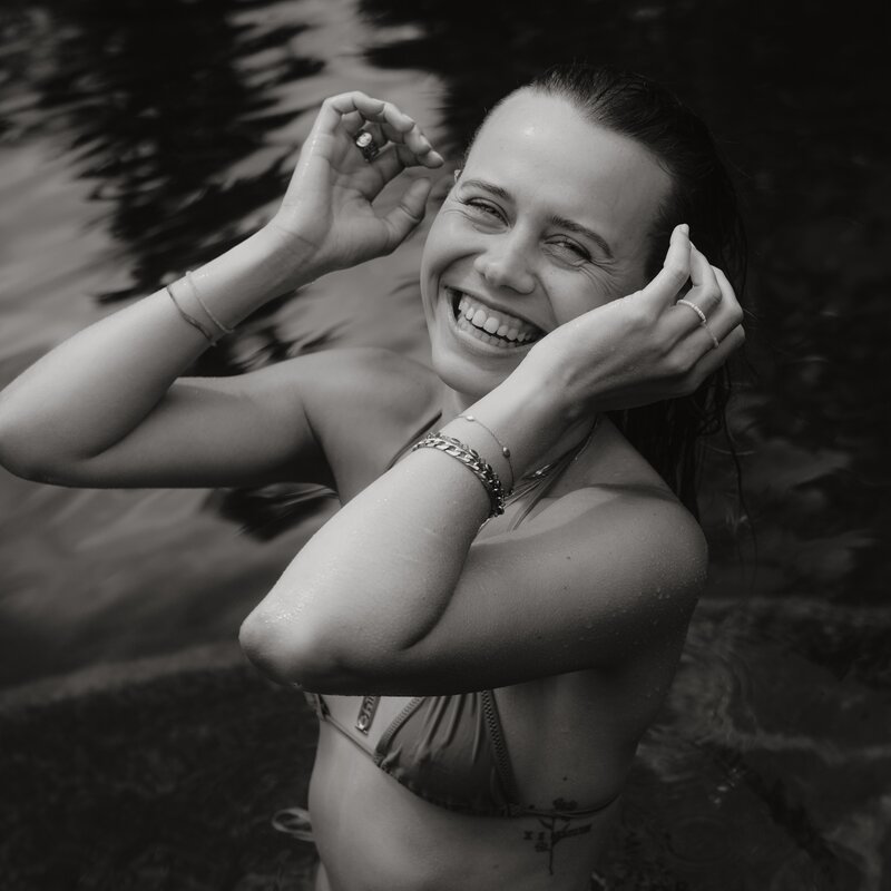 Smiling woman in water, adjusting her hair