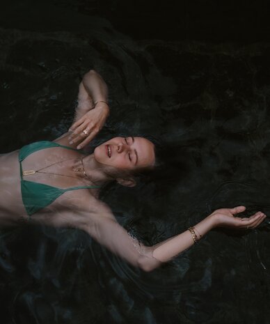 woman floating in dark water wearing a green bikini