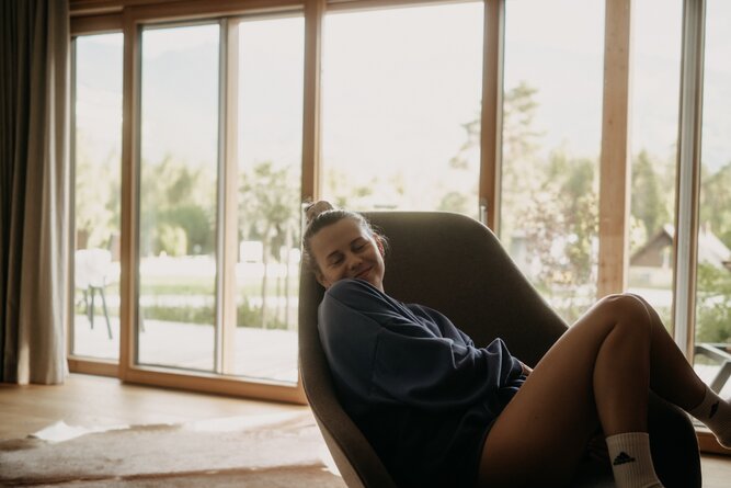 Person relaxing in a curved chair near large glass windows