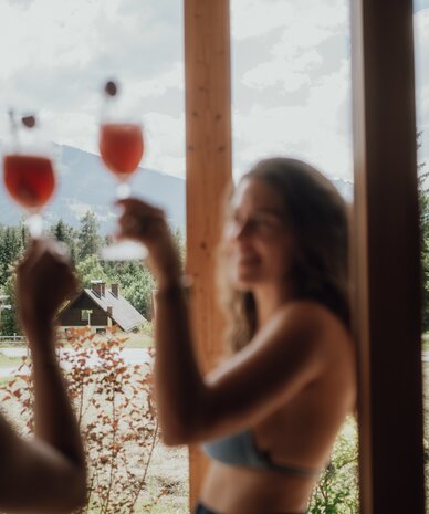 Blurry woman in bikini top raises a red drink outdoors