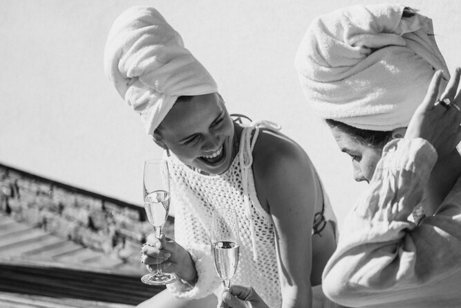 Two women with towels on their heads clinking champagne glasses.