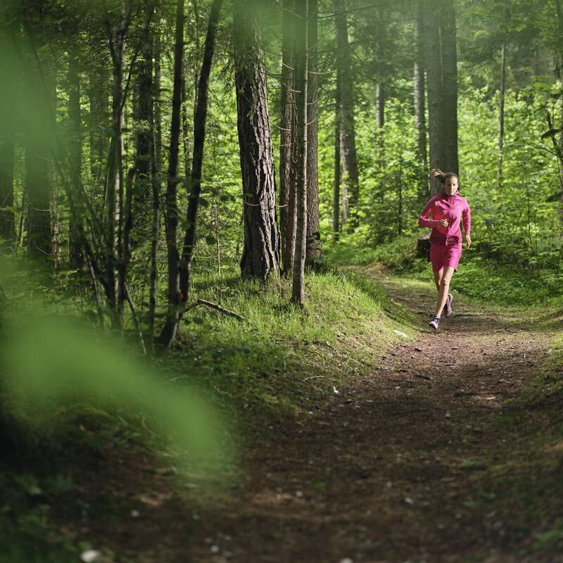 Person jogging along a forest path in pink clothing | © RAPHAELGABAUER.COM
