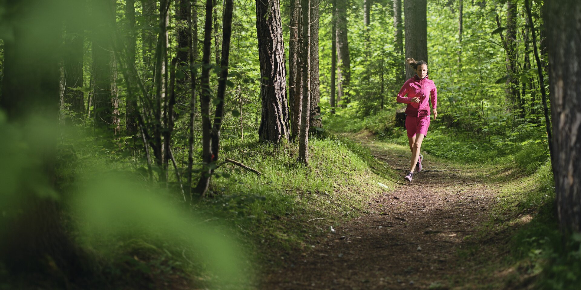 Person jogging along a forest path in pink clothing | © RAPHAELGABAUER.COM