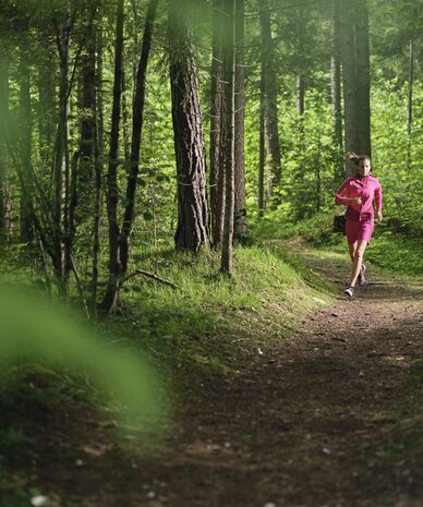 Person jogging along a forest path in pink clothing | © RAPHAELGABAUER.COM