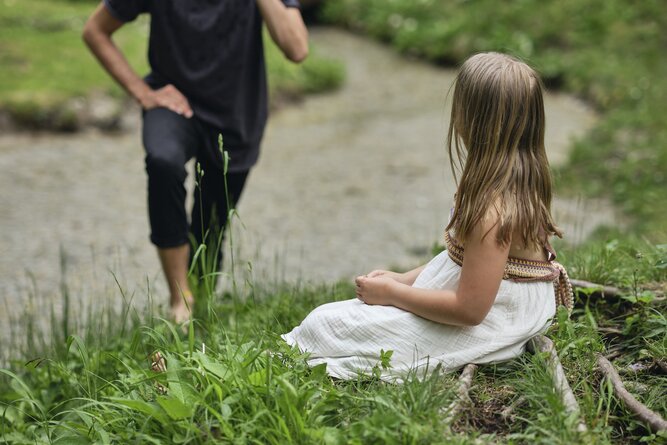 Man in black shirt offers flowers to girl outdoors. | © RAPHAELGABAUER.COM