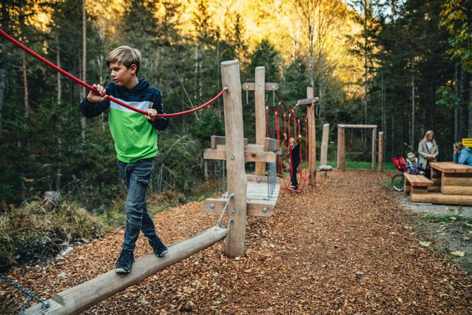 Child balancing on a wooden beam in an outdoor adventure park