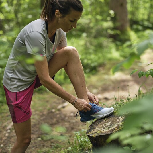 Woman tying running shoes on a forest trail | © RAPHAELGABAUER.COM