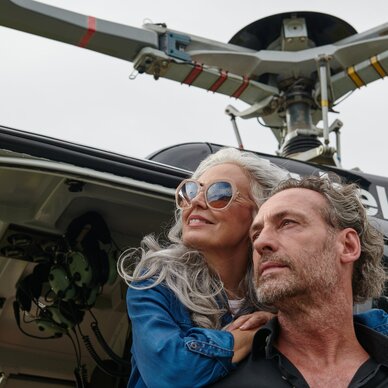 Two adults leaning from open helicopter door, gazing outward
