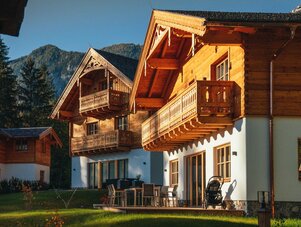 Two wooden alpine chalets with balconies in sunny yard