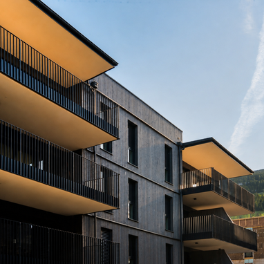 Modern residential building with orange balcony ceilings and black railings