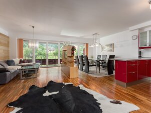 Open-plan living and dining area with red kitchen cabinets