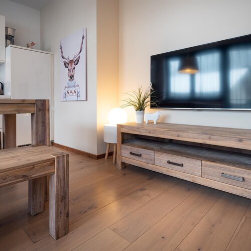 Open-plan living area with wooden furniture and mounted television