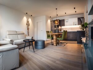 Open-plan living area with beige sofas, dining table, and green chairs