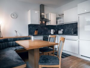 Modern white kitchen with marble backsplash and dining area
