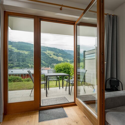 Interior room with wooden-framed glass door to balcony and hillside view