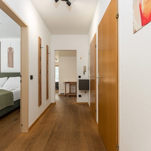 Hallway with wooden doors and a bedroom on the left.