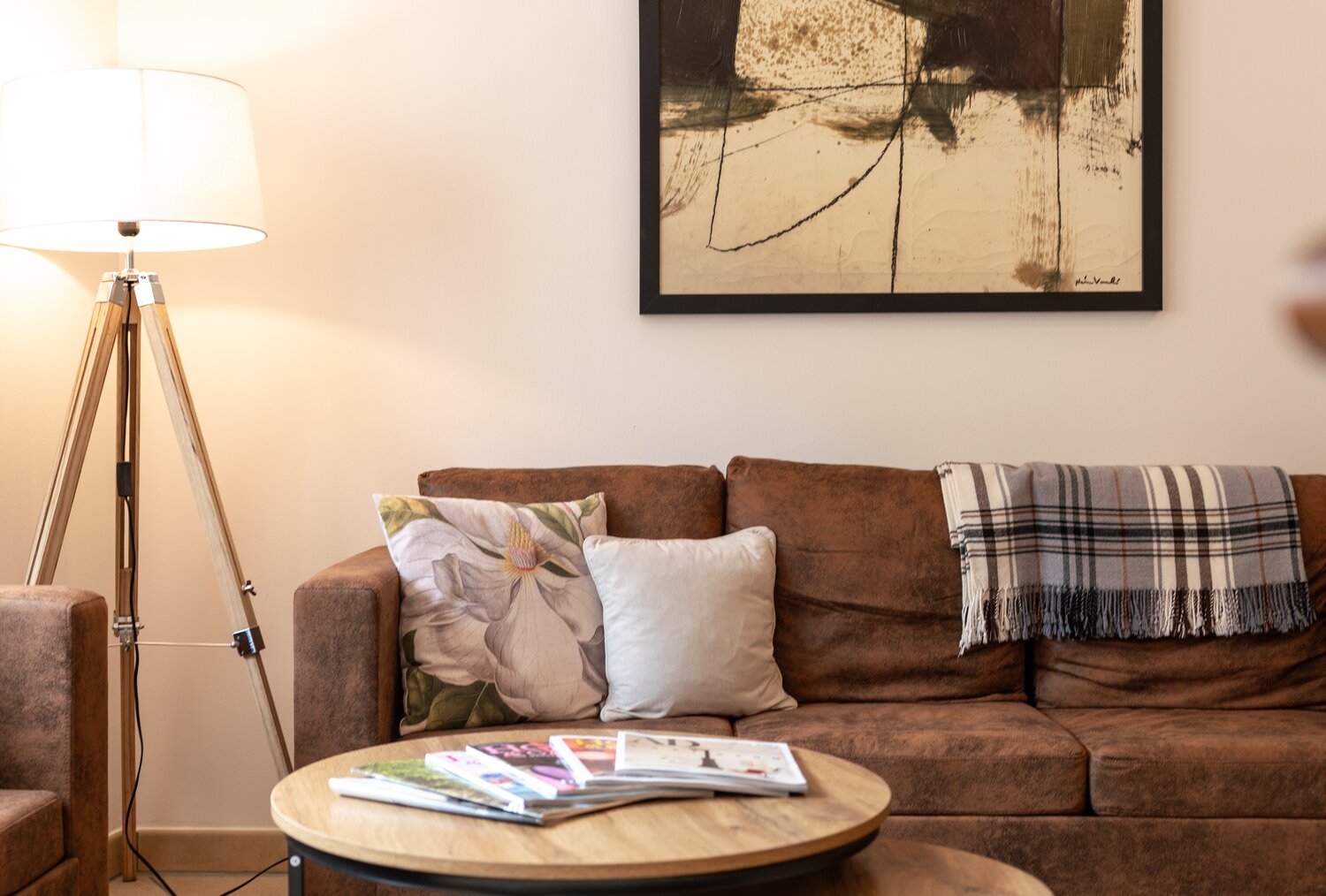 Cozy living room with brown sofa, coffee tables, and artwork.