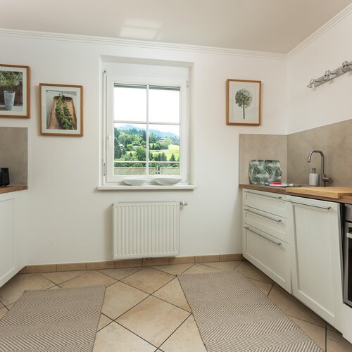 Bright modern kitchen with white cabinets, beige tiles and window view