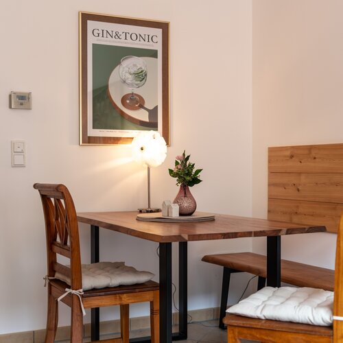 Cozy dining area with wooden table and chairs, wall art reading GIN&TONIC.