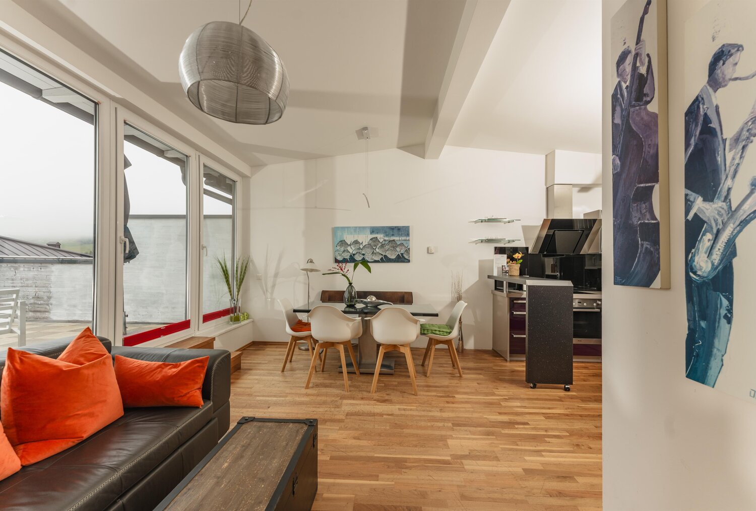 Open-plan living area with sofa, dining table, and large windows