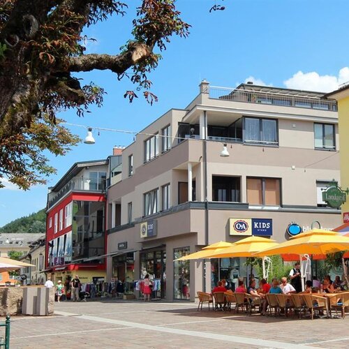 Outdoor cafe seating along a sunny street with buildings
