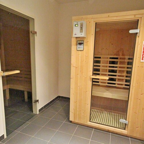 Wooden sauna room with glass door in tiled hallway