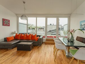 Bright open living room with gray sectional and orange cushions