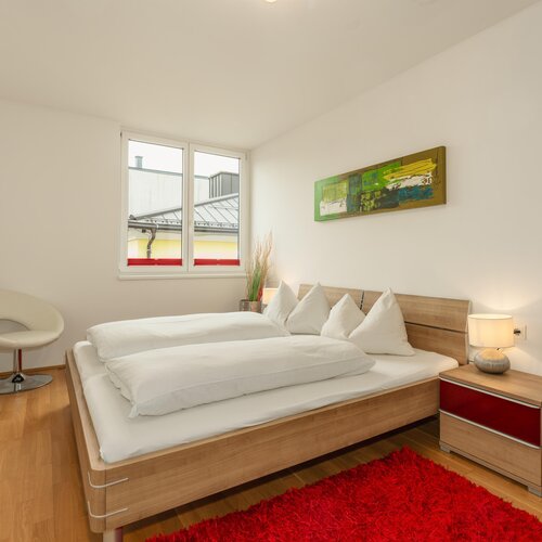 Modern bedroom with wooden bed frame and white linens