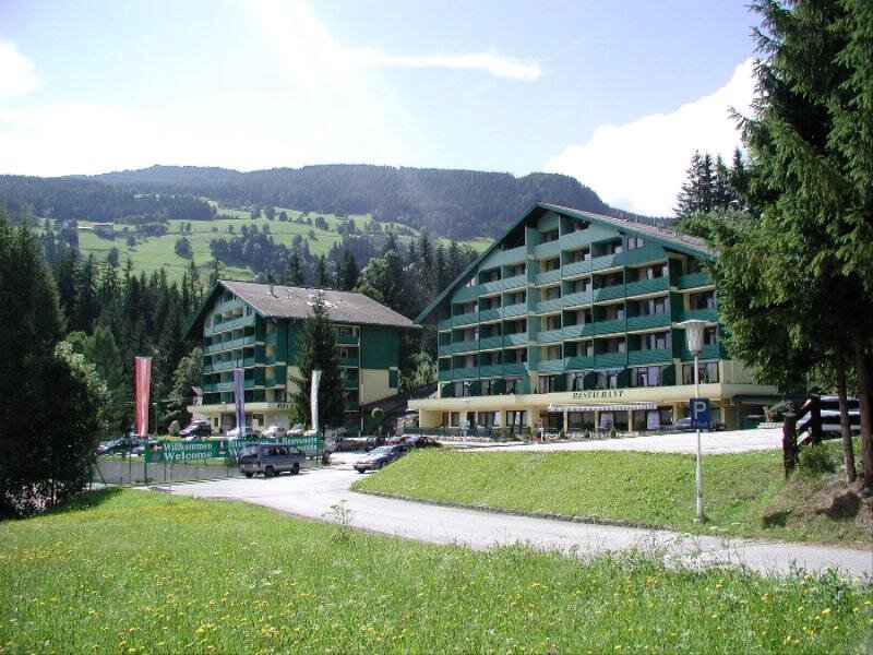 Two green alpine hotels with restaurant sign and welcome banners