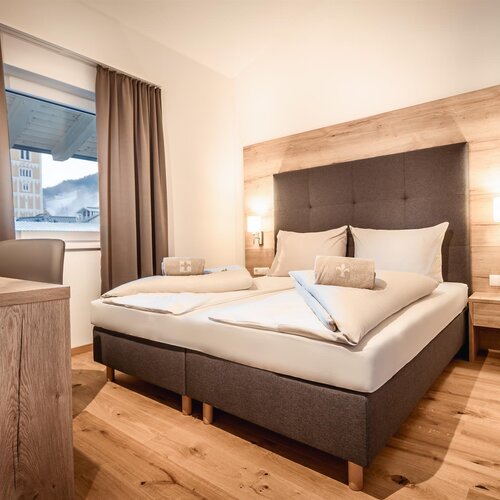 Hotel bedroom with a large bed, tufted headboard, and bedside lamps.
