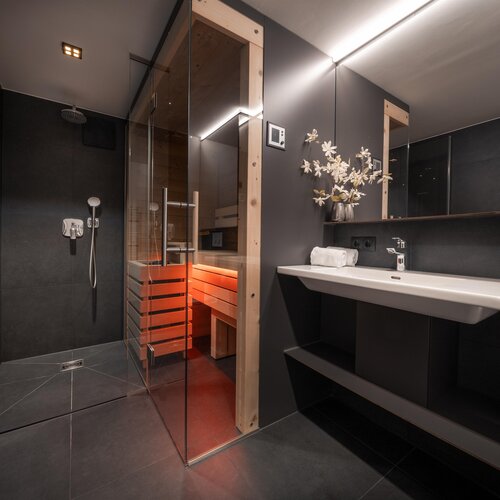 Modern bathroom with glass shower and wooden sauna.
