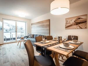 Open-plan living and dining area with a snowy balcony view