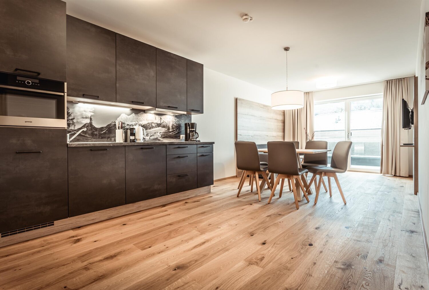 Open-plan kitchen with dark cabinets and dining table