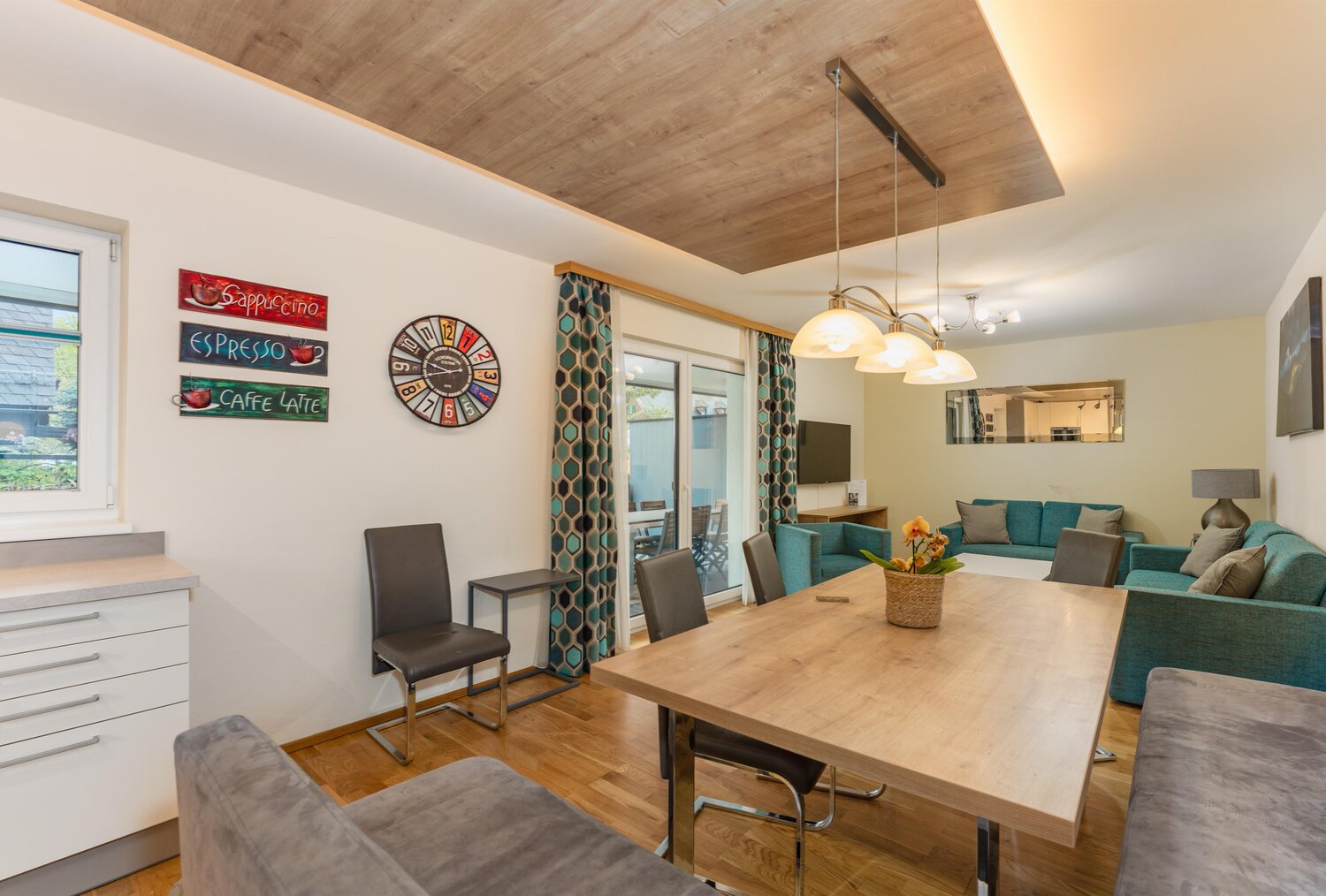 Open living and dining area with teal sofa and coffee wall art